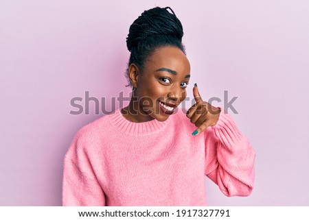 Young african american woman wearing casual winter sweater smiling doing phone gesture with hand and fingers like talking on the telephone. communicating concepts. 
