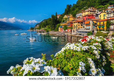 Flowery fence and colorful mediterranean buildings on the waterfront. Anchored boats in the harbor of Varenna, lake Como, Lombardy, Italy, Europe Royalty-Free Stock Photo #1917332807