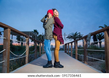 Couple of girlfriends hug each other at sunset