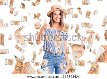 Young beautiful girl wearing hat and t shirt doing happy thumbs up gesture with hand. approving expression looking at the camera showing success.