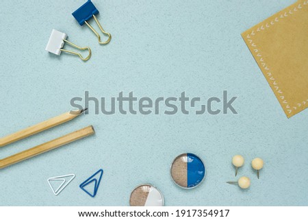 Flatlay wood pencil, white and blue paper clip, magnetic holder, bracket ,buttons, writing pad on a abstract blue background. Concept Office supply Store and business work.Close up.Texture.Copy spase.