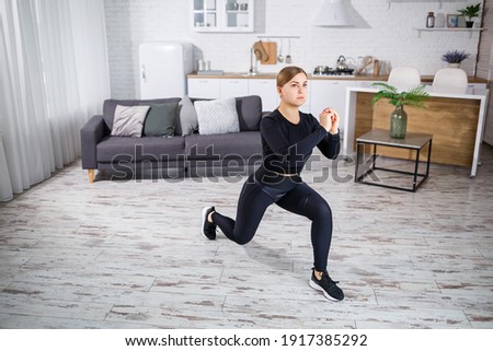 A young slender girl goes in for sports at home, she is dressed in fitness clothes, a black top and leggings. Fitness at home for a beautiful body