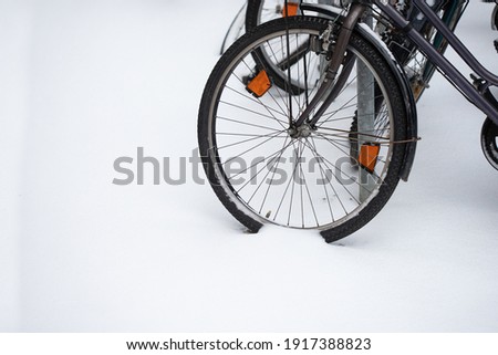 A closeup of a bicycle left outside on a street with a wheel stuck in snow. Choice of environmentally friendly transportation. Abstract monohrome texture closeup. Stock photography.