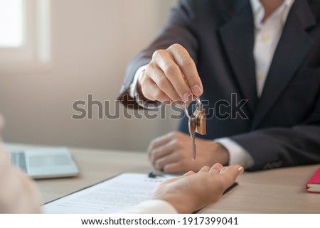 Close up hand of home,apartment agent or realtor was holding the key to the new landlord,tenant or rental.After the banker has approved and signed the purchase agreement successfully.Property concept. Royalty-Free Stock Photo #1917399041