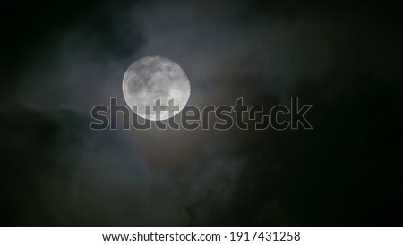 A picture of a phantasmagoric full moon in a cloudy and misty night