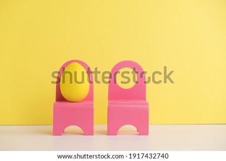 Easter holiday concept with cute eggs life. Different emotions and feelings. Lovely couple eggs sitting on pink chairs on yellow background