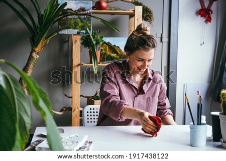 Young beautiful woman wipes her workplace in an art studio with a wet cloth.