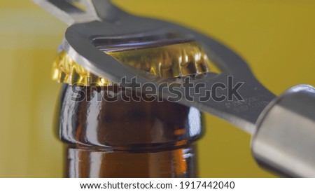 opening drink dark bottle with bottle opener on yellow background.