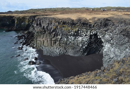 Towering basalt column cliffs and black sand beach on the coast of Iceland.