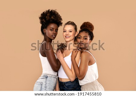 Three beautiful multi ethnic women posing together, looking at camera. Beauty portrait of two afro girl and one caucasian blonde. Skin care. Multiracial friendship.