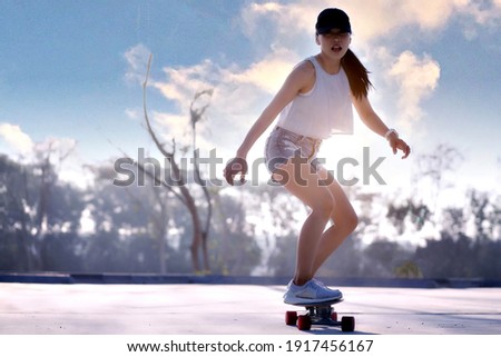 Asian women surf skate or skates board outdoors on beautiful summer day. Happy young women play surf skate at park on morning time. Royalty-Free Stock Photo #1917456167