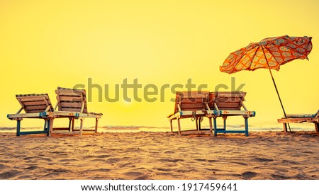 Beach chairs with umbrella on the tropical sand beach during sunset