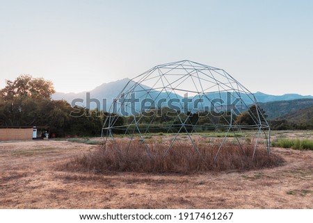 The steel frame of a geodesic dome is built on nature. Such a frame has a large load-bearing capacity and wind resistance Royalty-Free Stock Photo #1917461267
