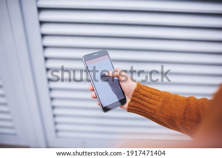 From above of crop anonymous male in casual clothes sanding on street typing message on  smartphone having free time