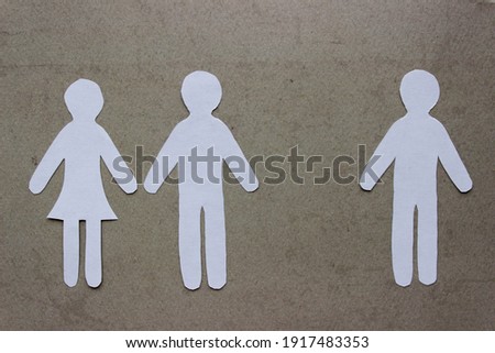 Silhouettes of people cut from paper. Couple holding hands and next to a lonely man. The concept of relationships, love, jealousy, loneliness, treason 