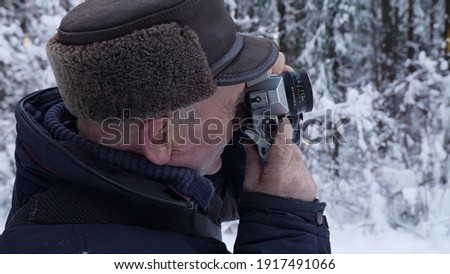 amateur photographer is taking picture of winter nature in forest, snowy woodland with trees
