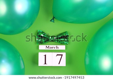 St Patrick's Day greeting card. Block calendar, balloons and bow tie on green background