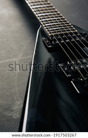 Crop soft focus shot of black V shape electric guitar on dark grunge background