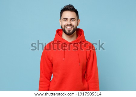 Young caucasian smiling happy cheerful bearded attractive handsome student man 20s wearing casual red orange hoodie looking camera isolated on blue background studio portrait People lifestyle concept Royalty-Free Stock Photo #1917505514