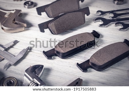 New car brake pads on a white wooden background. Studio photo with vignetting.