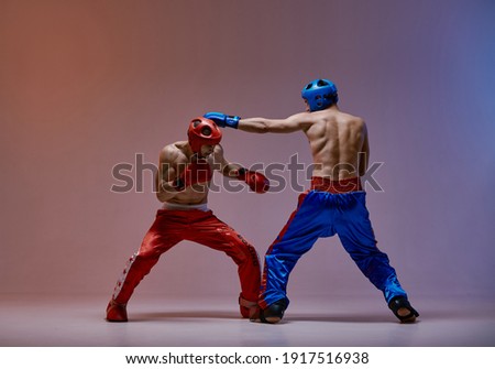 Sparring of two fighting males in boxing gloves during battle, martial arts, mixed fight workout