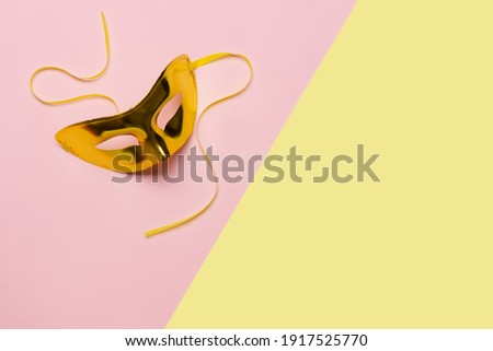 Gold carnival mask on yellow-pink background. Top view. Banner