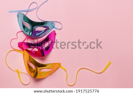 Multicolored carnival mask on pink background. Top view. Banner