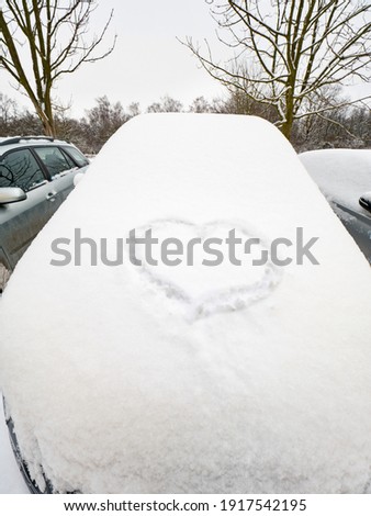 Big lovely heart drawn in the snow on car. Fresh powder snow.