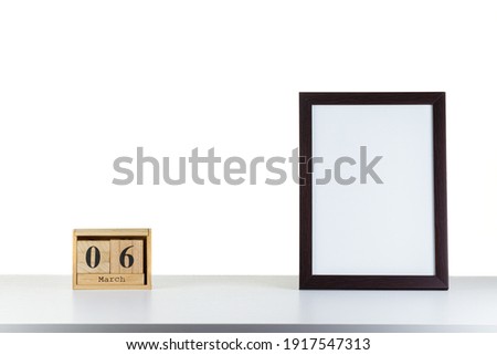 Wooden calendar 06 march with frame for photo on white table and background  close-up