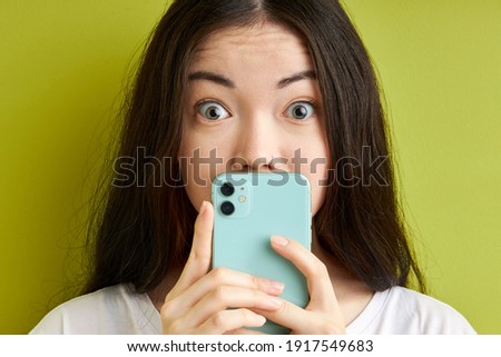 woman read unbelievable social media information, use smartphone read blog post impressed hide screen stare stupor isolated over bright green color background