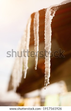 Close-up of an icicle hanging from the roof of a house. 