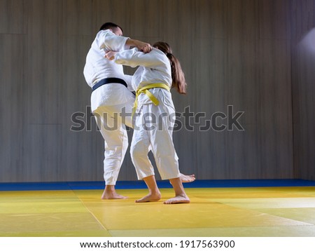 Black belt judoka demonstrating o soto gari technique on young female student Royalty-Free Stock Photo #1917563900
