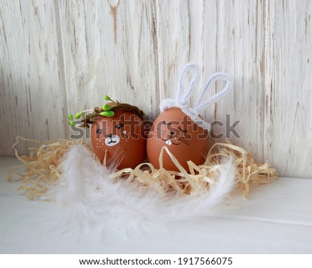 DIY Easter animals from eggs, cute faces, a hare with white ears and a bear cub in a spring wreath on a wooden natural background, decor for the holiday