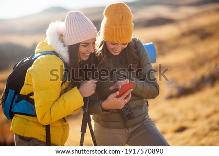Two female backpackers using phone outdoor