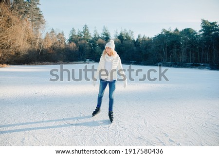 Woman skates on a frozen lake in forest. Ice skating on a frozen canal. Winter in Germany. Snow in East Frisia. 