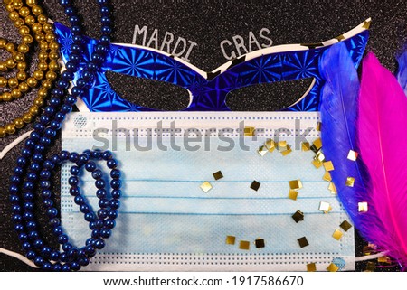Mardi Gras Masks Behind Medical Facemask With Bead Strings And Feathers