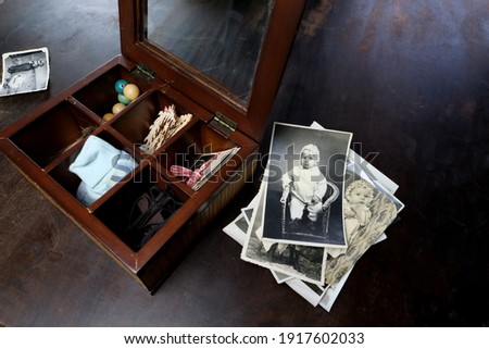 female hands fingering memorabilia in an old wooden box, a stack of retro photos, a lock of hair, vintage photographs of 1960, concept of family tree, genealogy, childhood memories