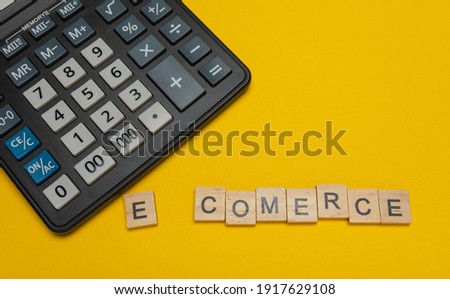 Phrase or word - e-comerce. Wooden block letter word and modern calculator on a yellow background, business concept with space for text