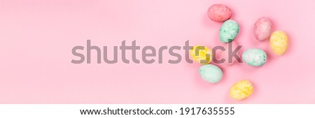 Hand colored easter eggs on light pink abstract background. Top horizontal view copyspace. 