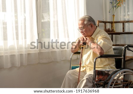Lonely Asian Senior man was sick and sitting on wheelchair. Retirement age lifestyle and stay at home alone. Royalty-Free Stock Photo #1917636968