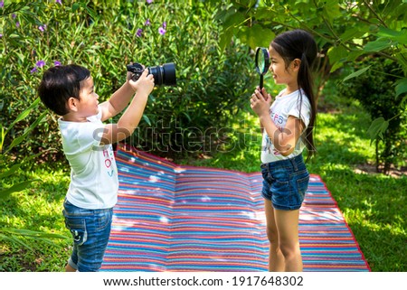 Children learning about camer in the garden. Asian boy playing taking pictures.
