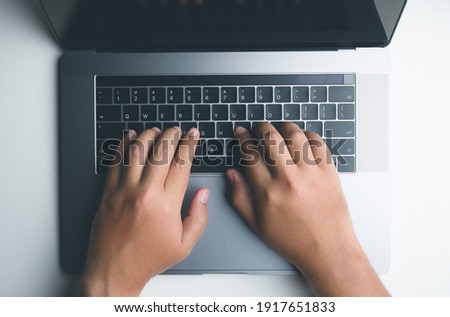 Top view of people hand typing on laptop keyboard to use socia lnetworks,working or business.Flat lay design.