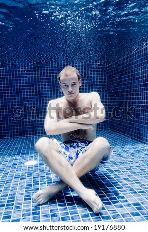 An underwater shot of a man in a swimming pool holding his breath