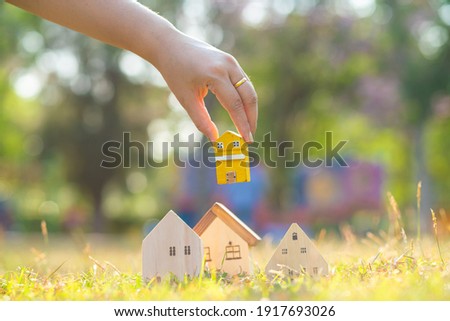 Hand choose wooden house on green grass saving concept for buying a home idea of investment funds