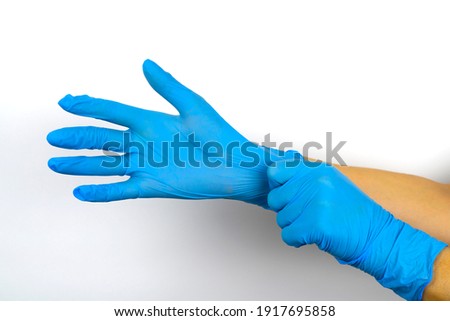 Hands put on blue medical gloves on a white background. Means of protecting medical workers from viruses. Royalty-Free Stock Photo #1917695858