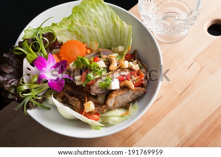 Thai Salad with Crispy Duck and fresh green mango tomatoes and cashew nuts on a bed of lettuce.
