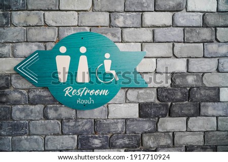 WC - Toilets icon, Public restroom sign with a male and female symbol and direction on a brick wall background.