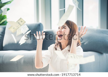 Happy young asian woman holding dollar money and throw in the air celebrate happiness dance wealth lottery money rain drop. Winner Success business woman throw cash flow Happy money smiling face Royalty-Free Stock Photo #1917713714