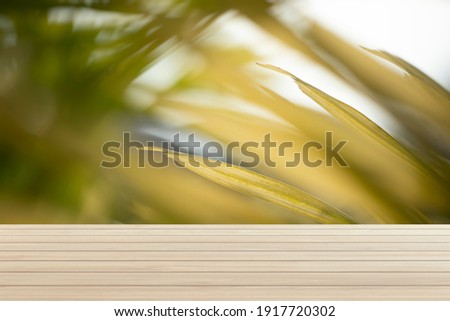 Textures on an empty wooden table and a blurred Yellow backyard. Can be used as a background for presenting products.