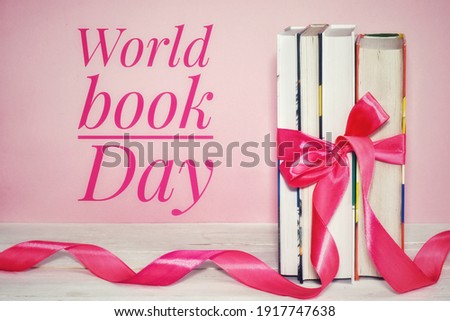 A stack of books tied with a pink ribbon on a pink background. World Book Day poster.